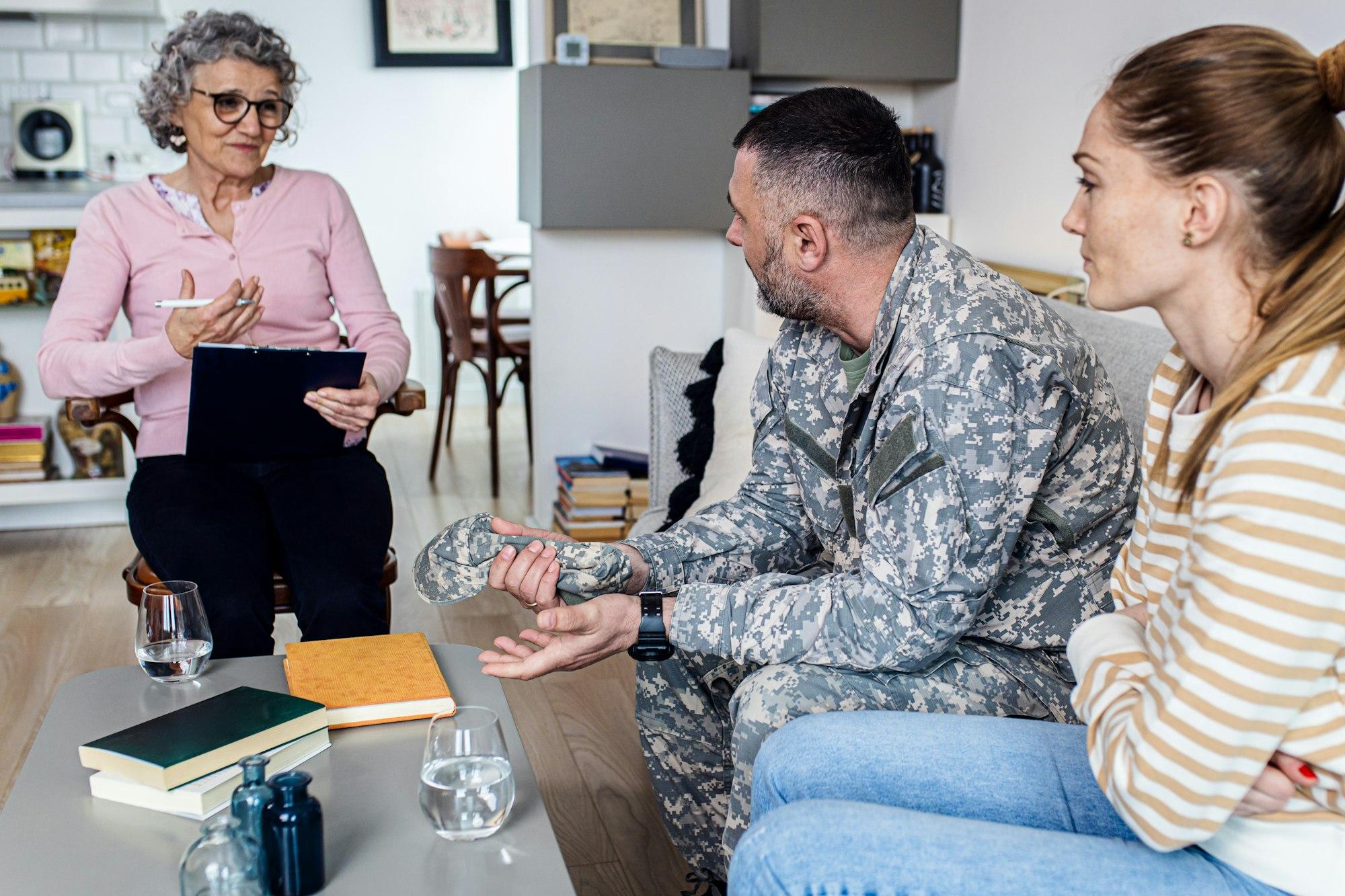 Soldier with his wife having therapy meeting with senior female psychologist.