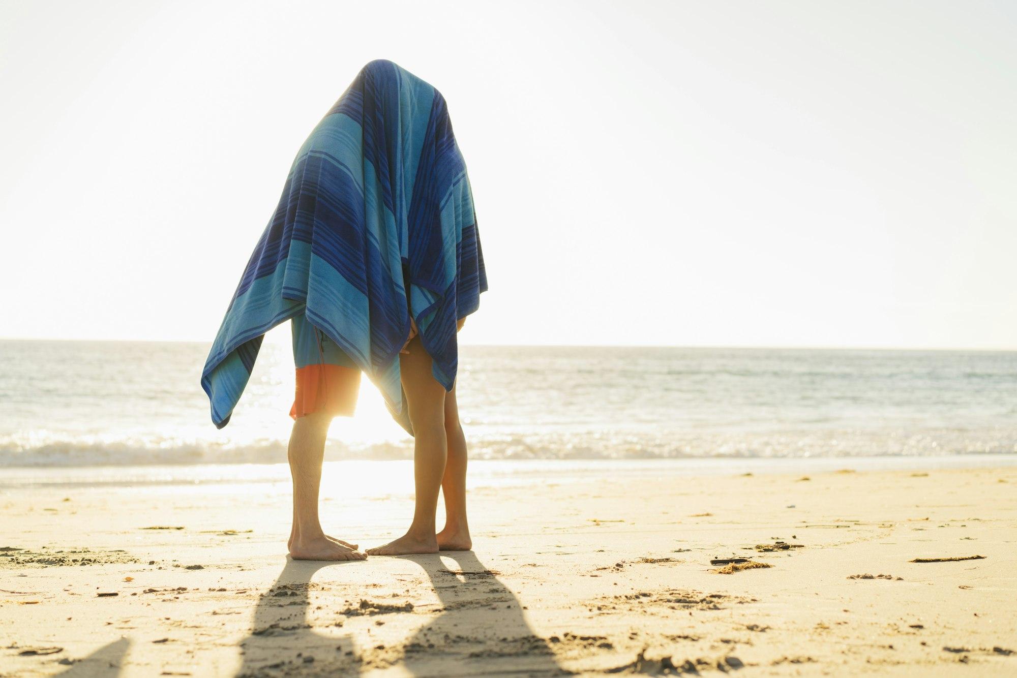 Couple hiding under blanket on Newport Beach, California, USA