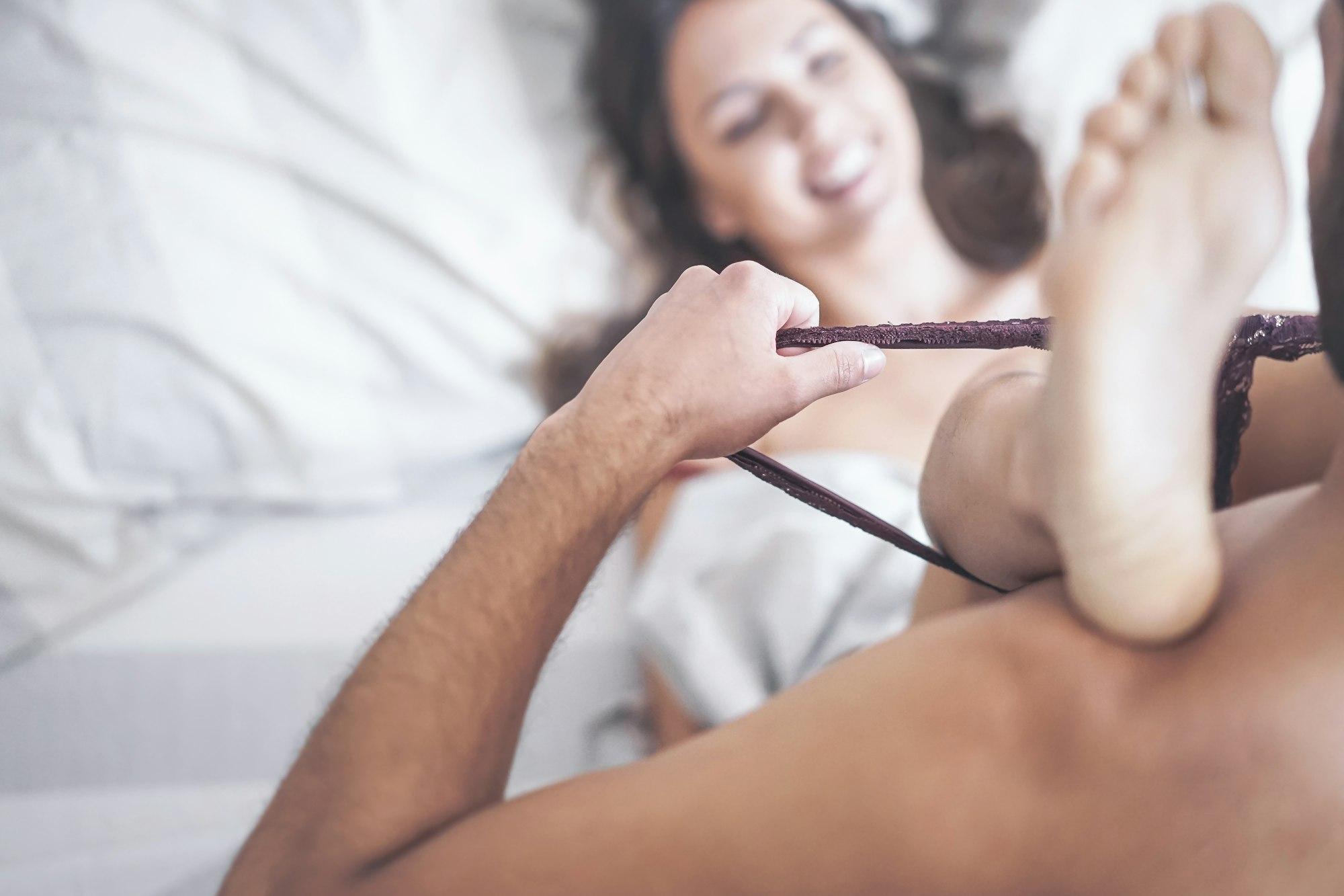 Boyfriend putting off his girlfriend's panties before having sex on bed