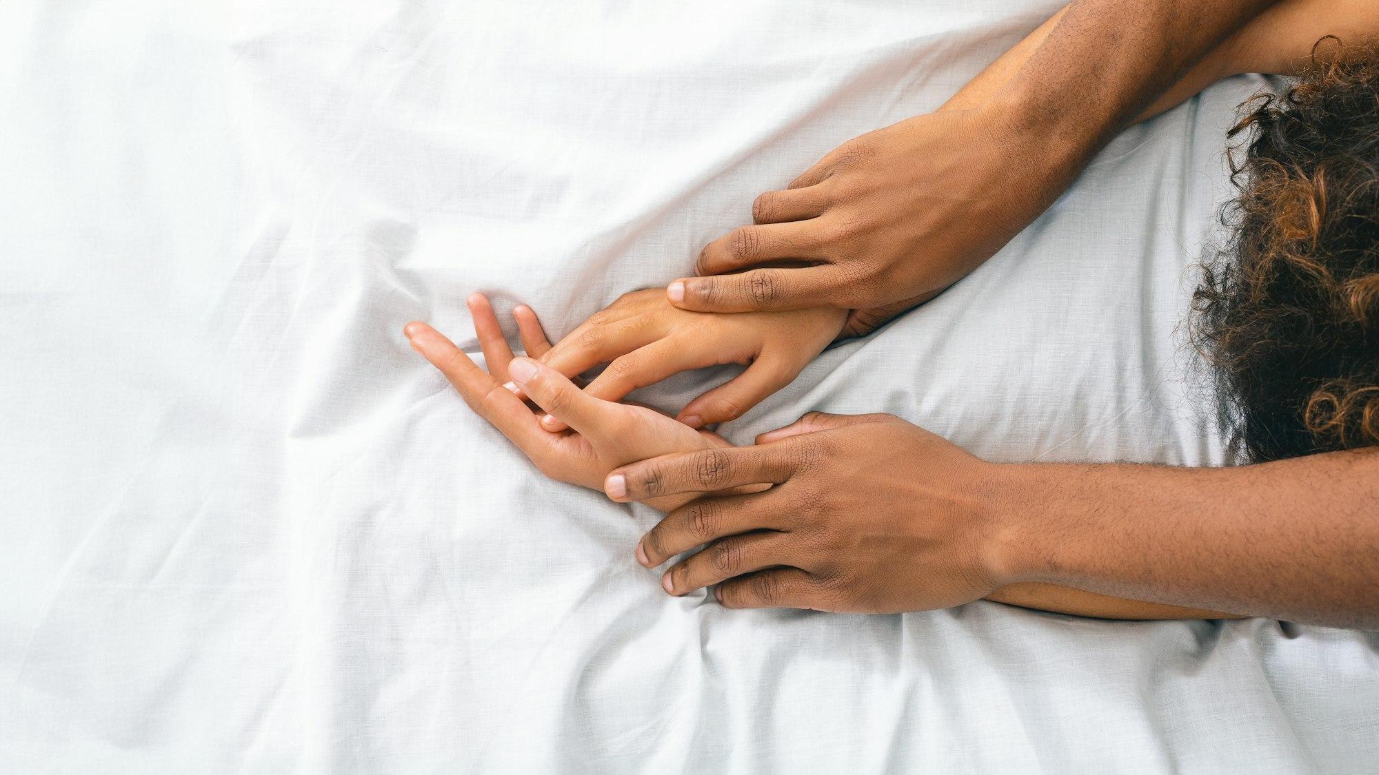 Man and woman hands having sex on bed