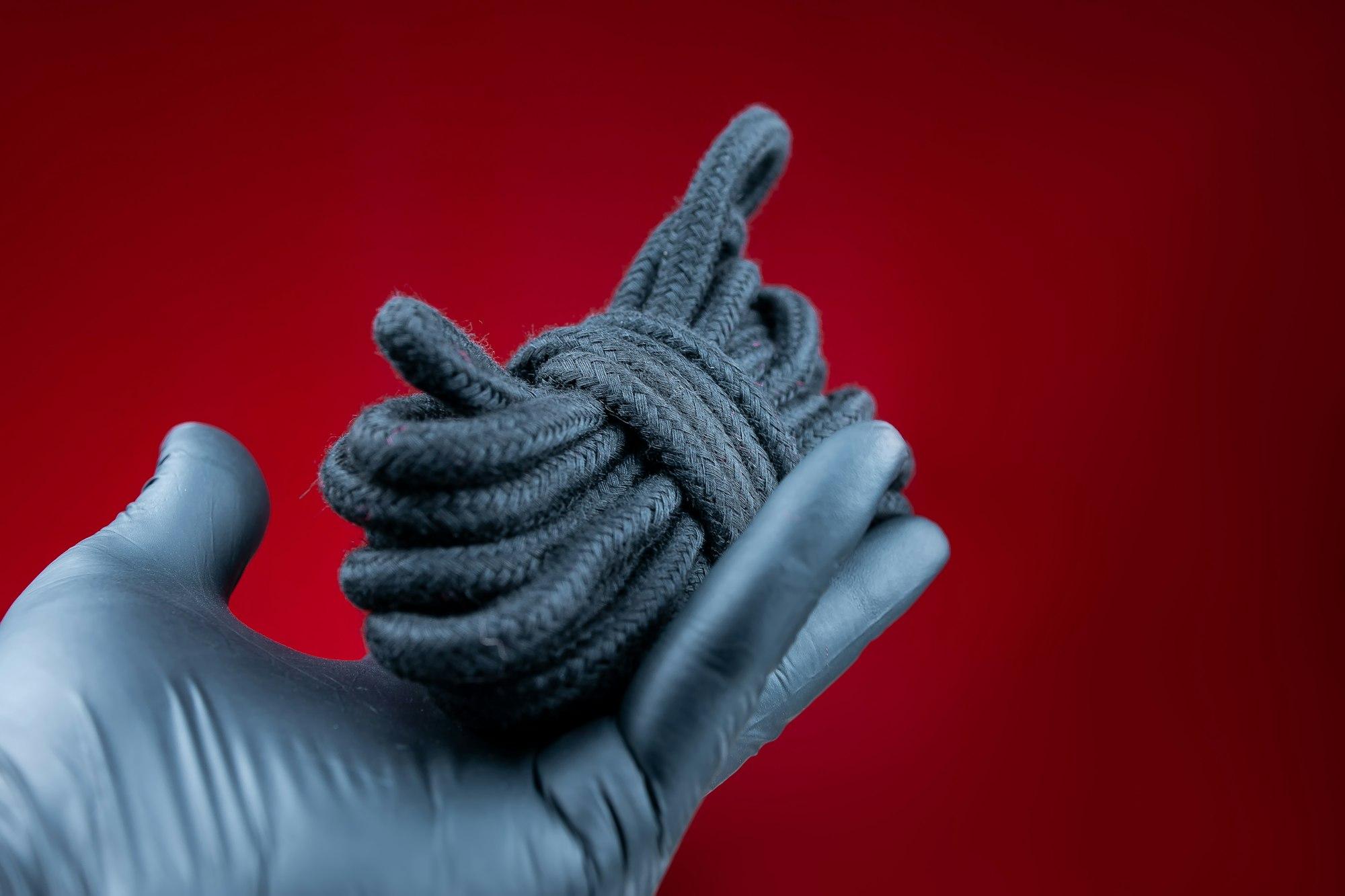 hands in black gloves holding a rope for bondage and erotic bdsm games