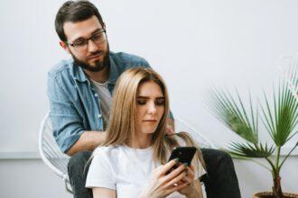 Husband watches as wife uses smartphone.