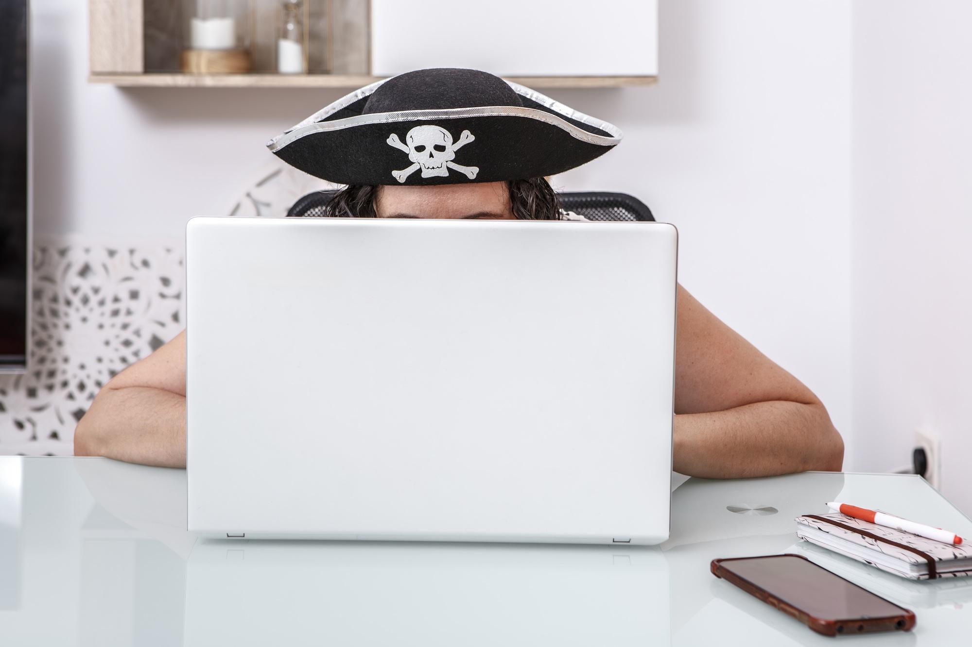 Pirate-Themed Hacker Engaging in Online Scams at a Modern Home Office