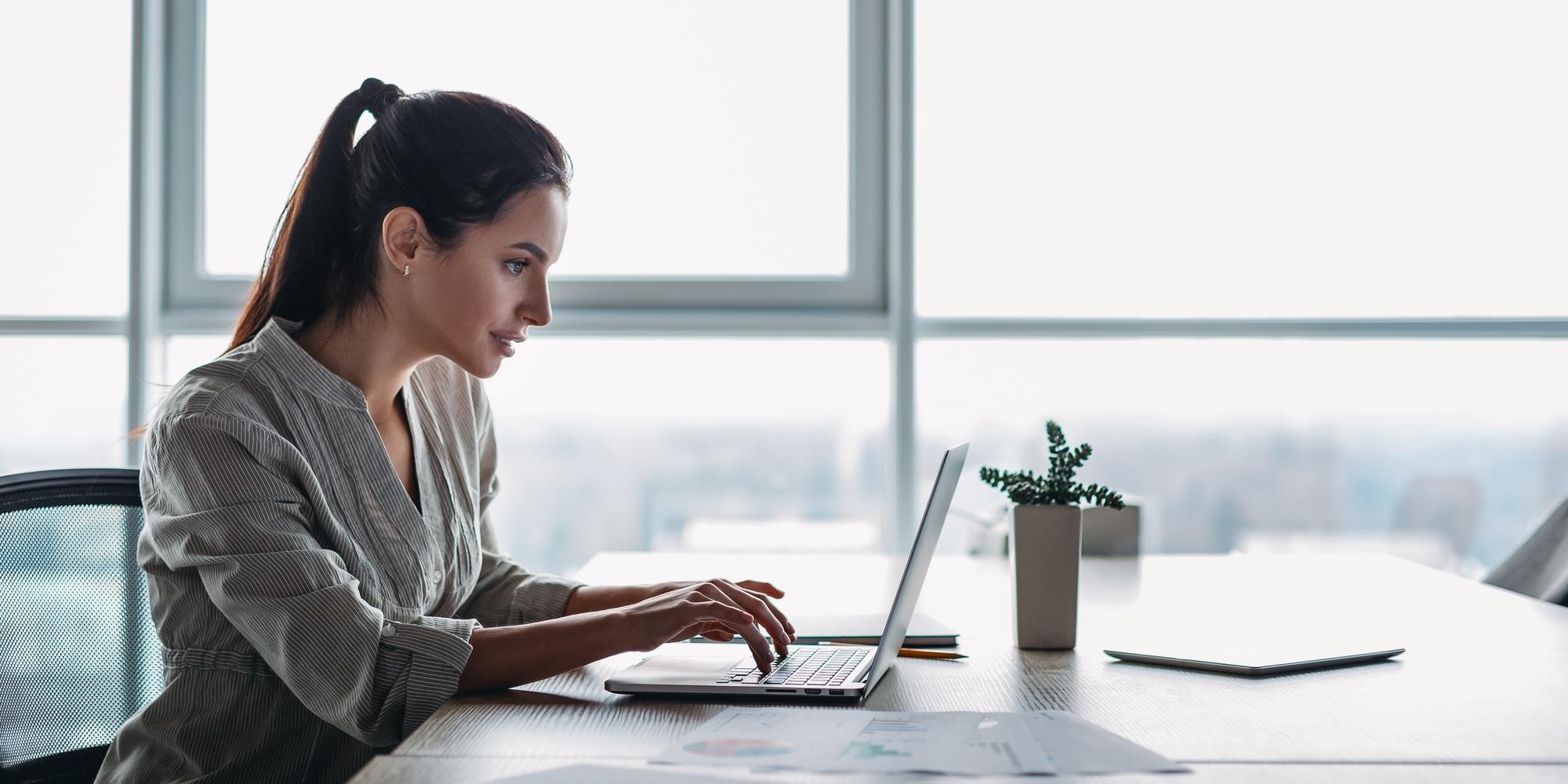 Website header of Portrait of gorgeous, smiling young female using laptop computer at workplace