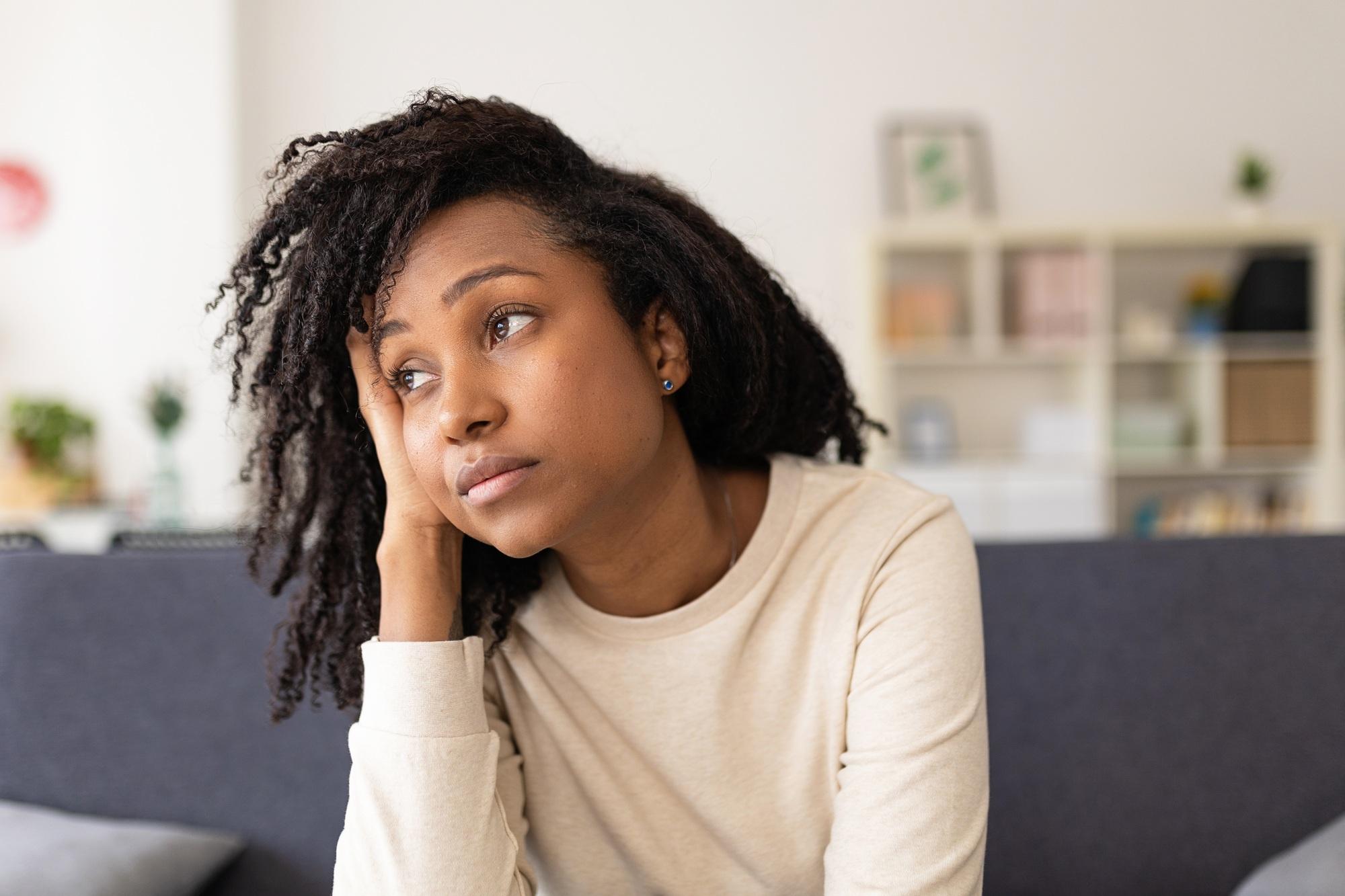 Worried woman thinking about her problems while sitting on a sofa at home