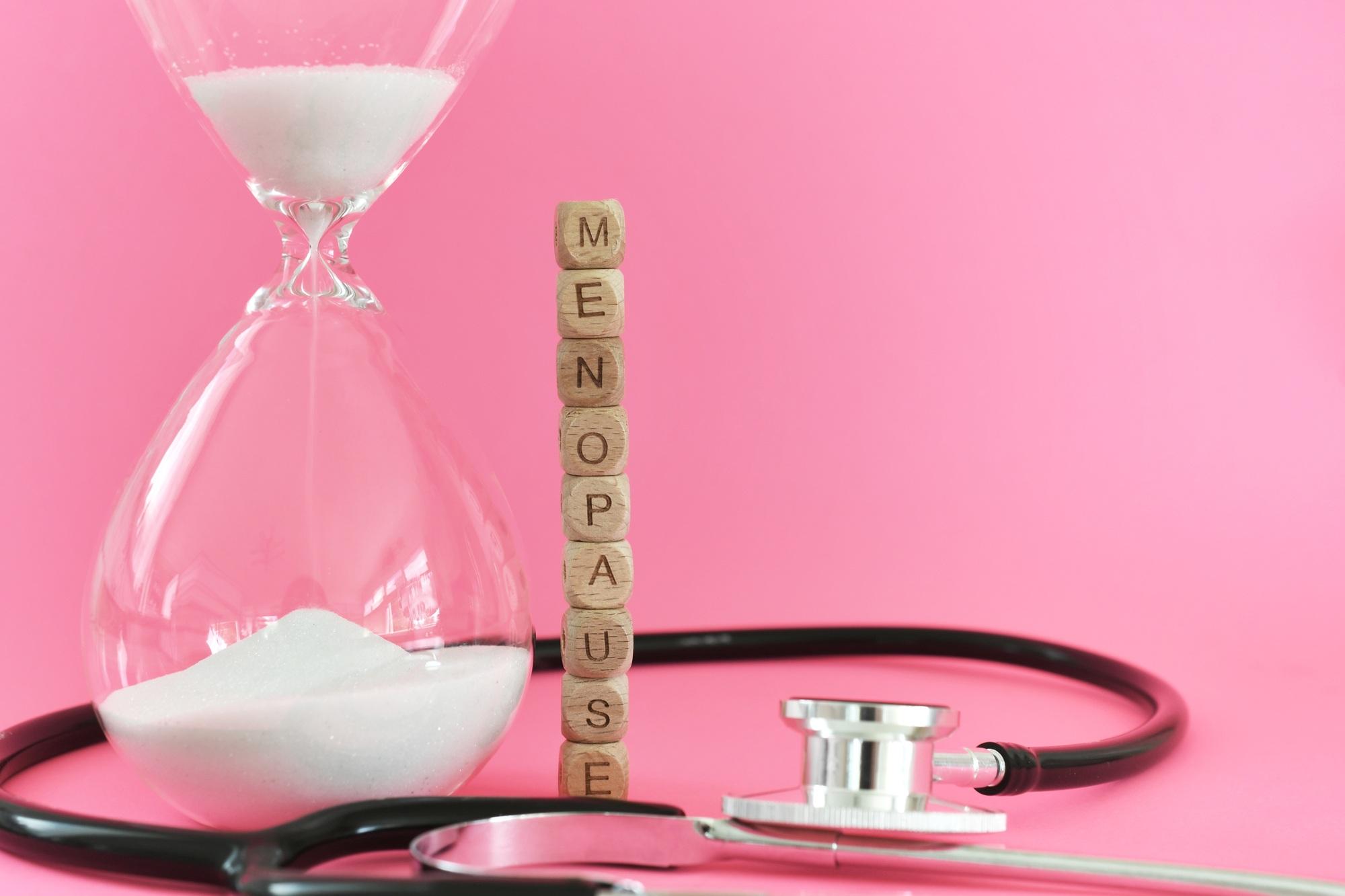 Menopause with stethoscope and hourglass on pink background. Going through the change.