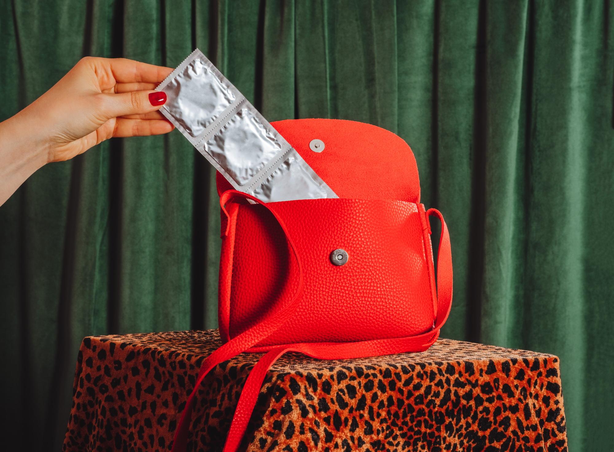 Woman's hand takes pack of condoms out of her purse