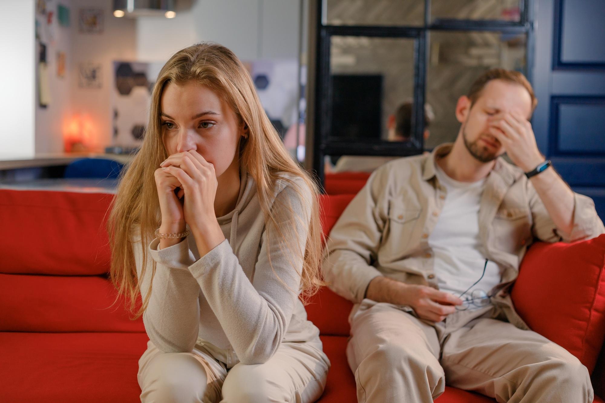 Young couple in relationship crisis. Offended man and woman sitting separately sofa in living room