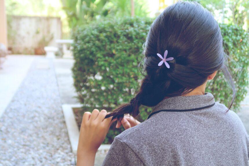 Woman braiding her own hair.