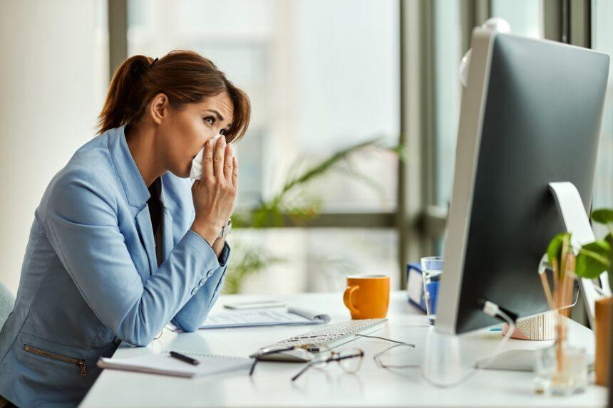 Young businesswoman blowing nose while working in the office.