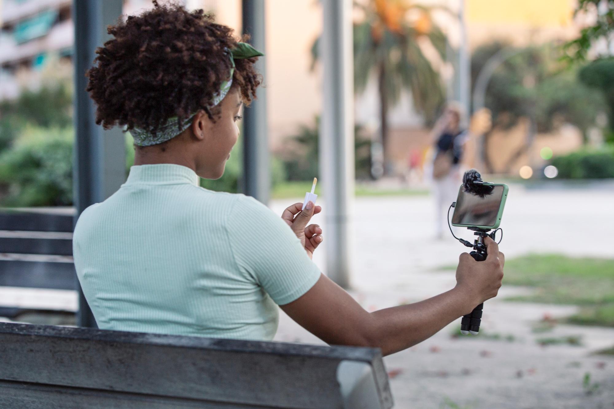 Afro young man streaming makeup tips for his followers on social media.