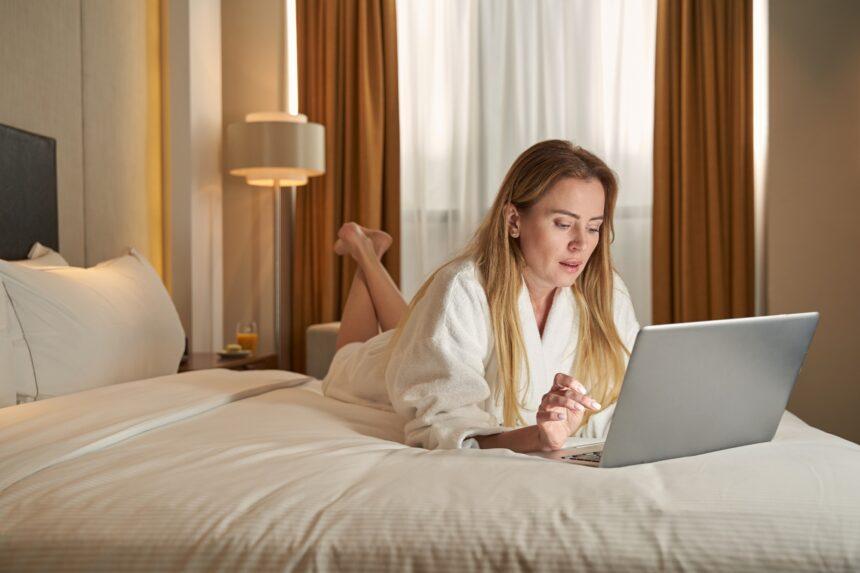 Working woman on bed clicking on laptop
