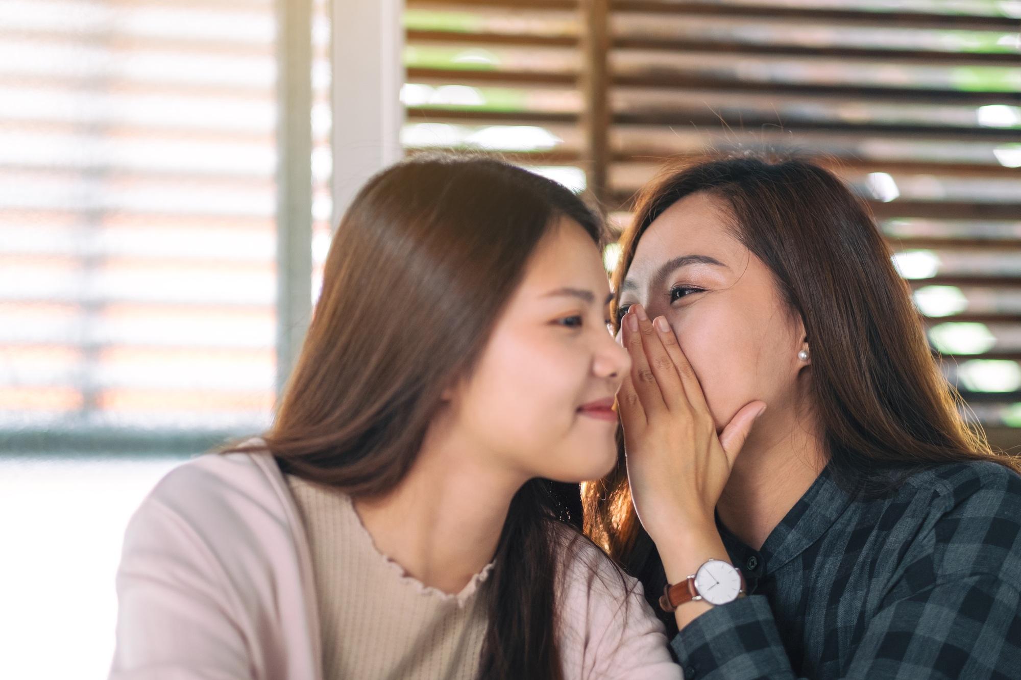 Two female friends telling and gossiping the secret