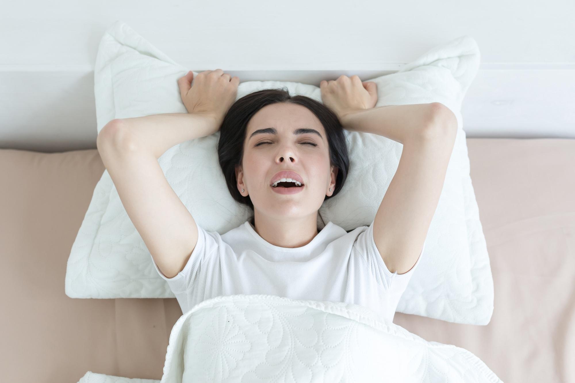 A beautiful woman lies in bed, enjoys an orgasm, alone at home