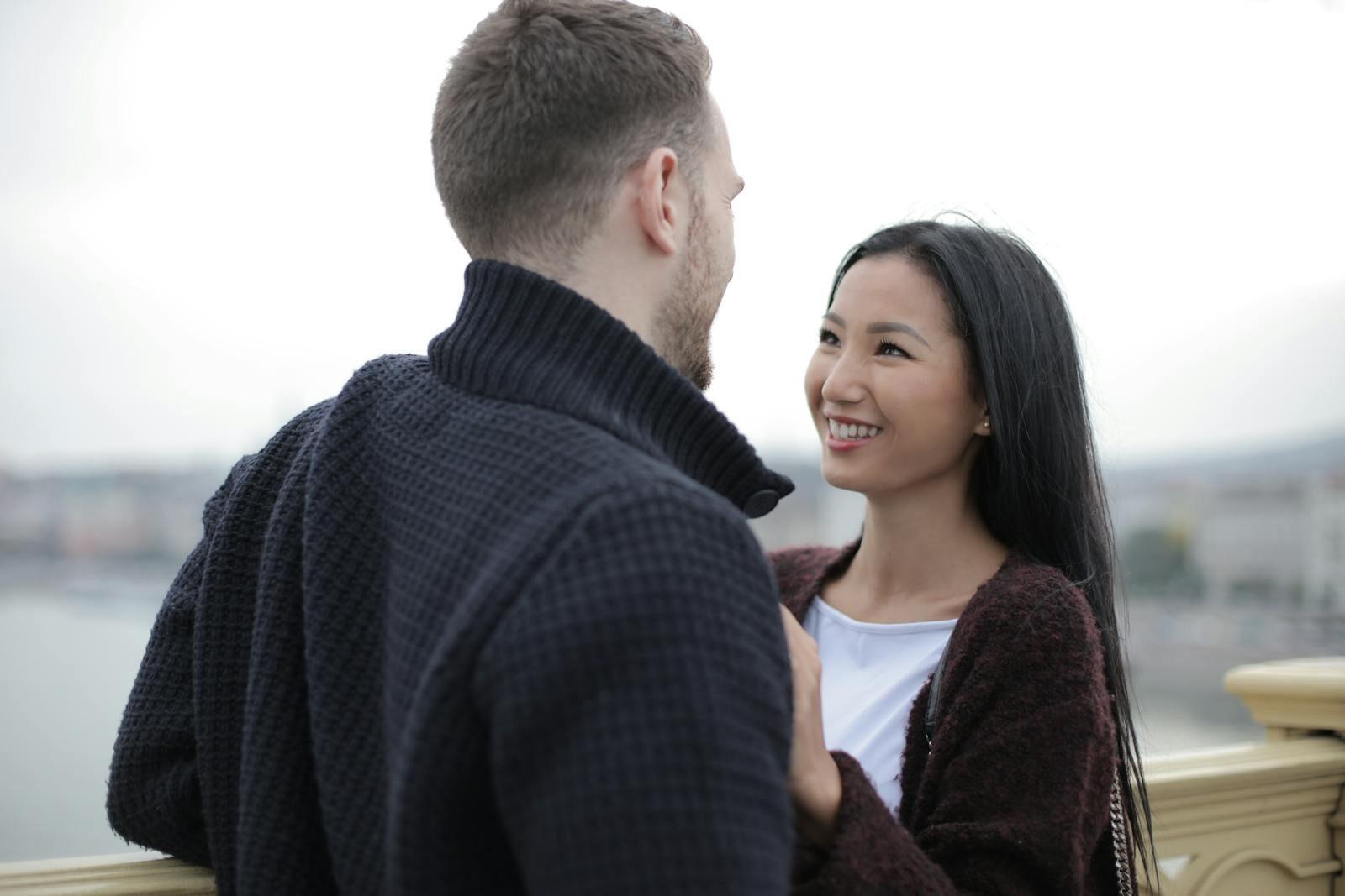 A happy couple smiling and enjoying a romantic moment together outdoors during the day.