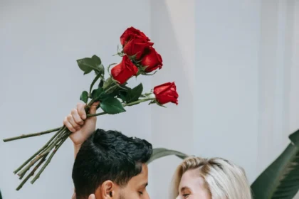Affectionate couple embracing indoors with a bouquet of red roses, symbolizing love.